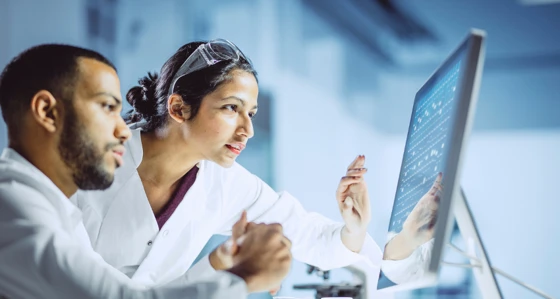 Two lab workers looking at a screen
