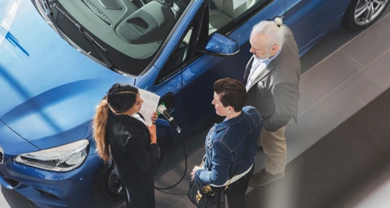 People having a conversation next to an electric car