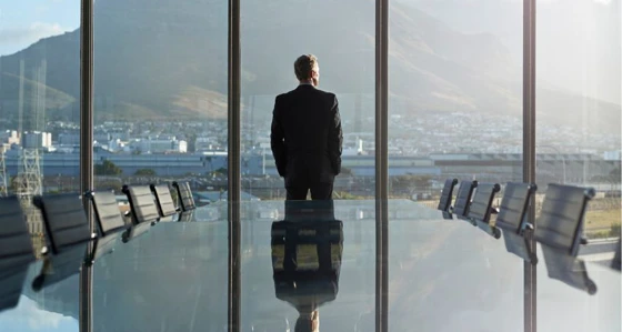 Man in boardroom looking out the window to a landscape view