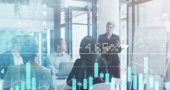 Businesspeople meeting in the boardroom superimposed over a graph showing the ups and downs of the stock market
