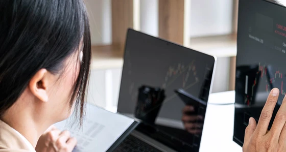 A woman touching a screen displaying stocks index prices