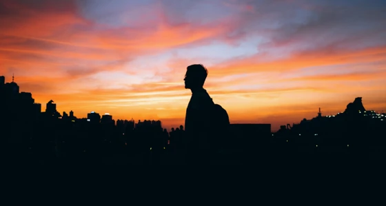 Silhouette of man in front of cityscape against sky during sunset