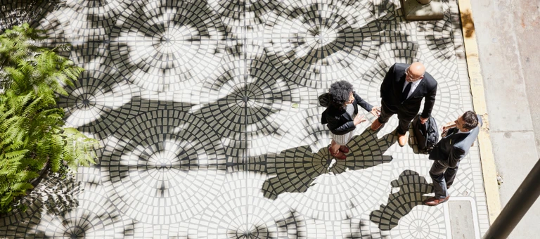 Three business people having a conversation on tree lined sidewalk