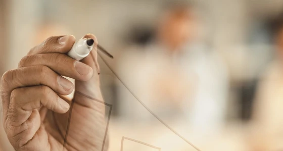 A man drawing a graph on a transparent wall