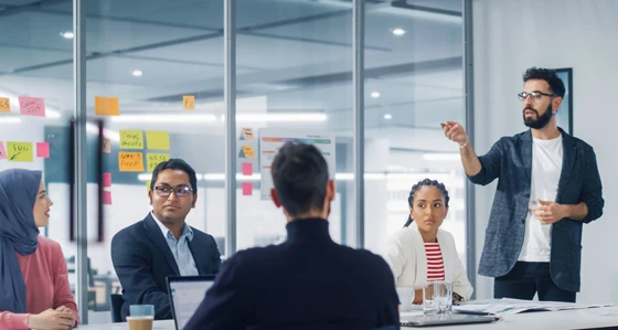 A meeting with a man standing up giving a presentation
