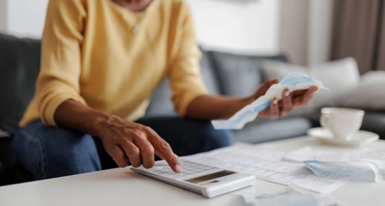 Woman using a calculator while looking at her bills