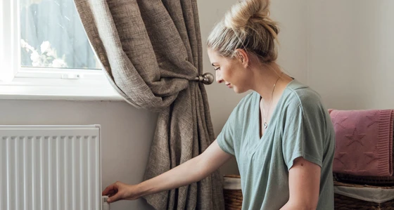 A woman adjusting a radiator in her home